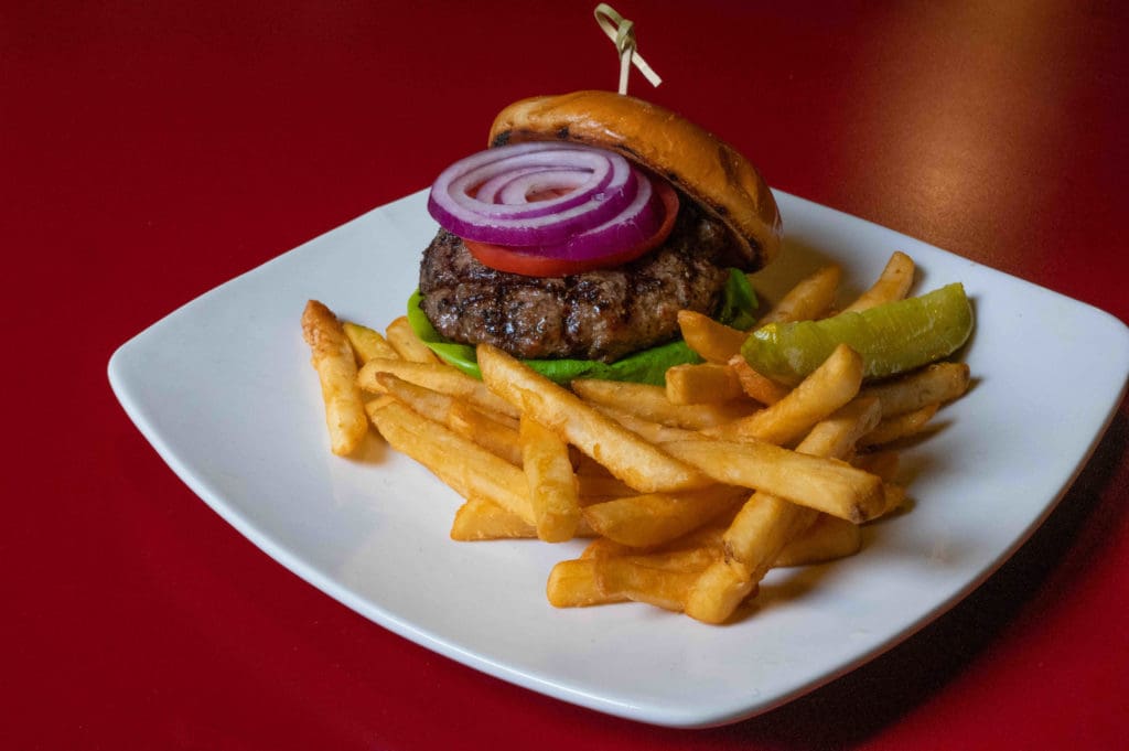 An up-close image of a burger with a toasted bun and fries.